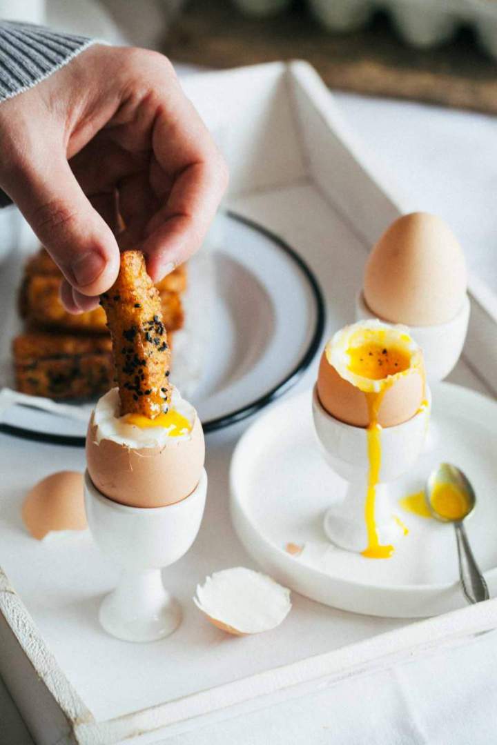 Dipping savory french toast into soft boiled eggs for breakfast