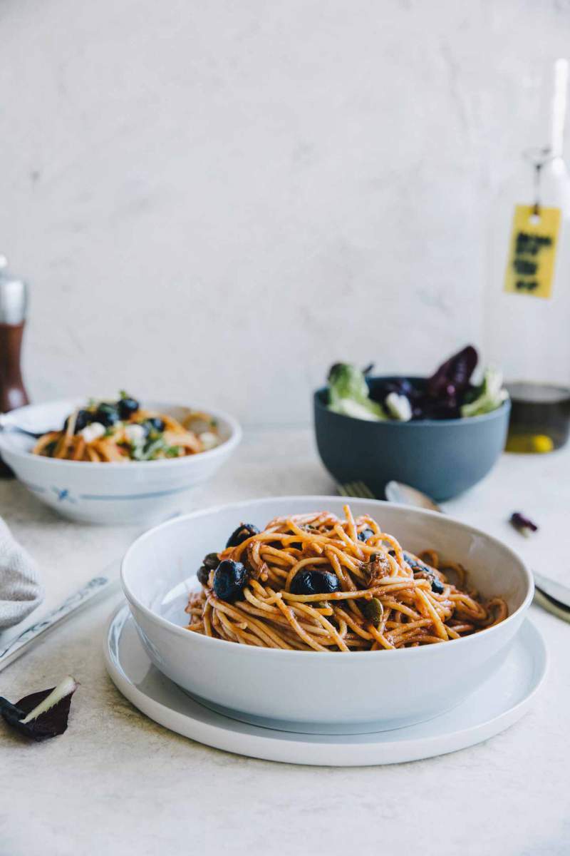 Špageti Puttanesca postreženi v krožniku
