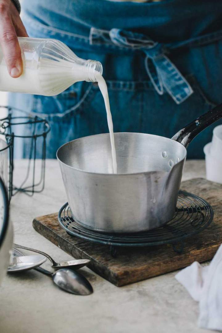 Pouring milk into a saucepan for Homemade Mascarpone